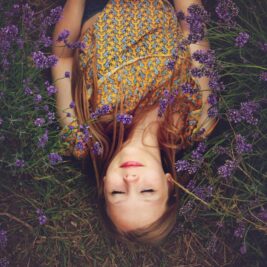woman in yellow and teal top sleeping beside lavenders