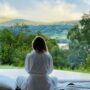 sitting woman in white robe looking at mountains during daytime
